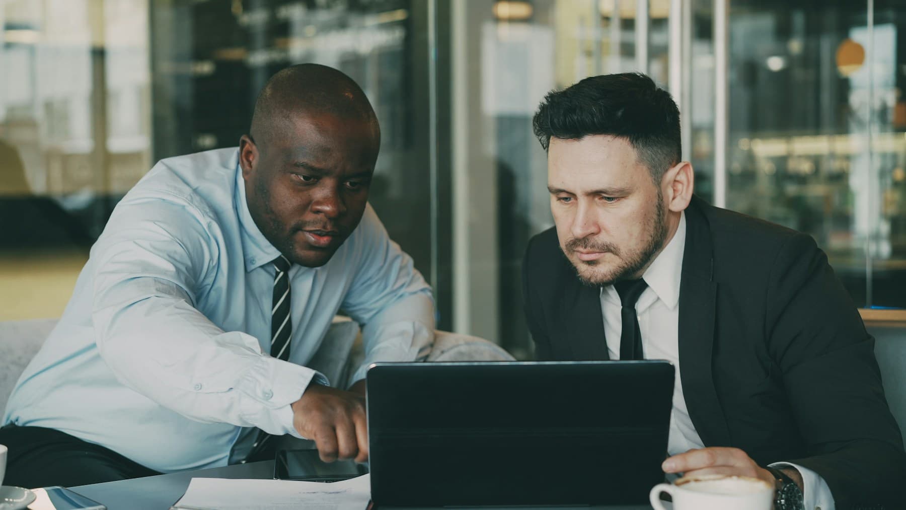 Two men discussing a project while looking at the same laptop.